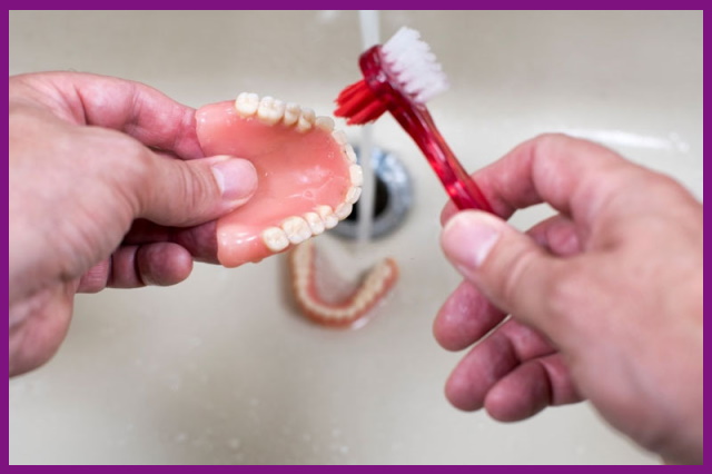 cần chải hàm giả dưới vòi nước lạnh để đảm bảo lấy sạch hết các cặn thừa thức ăn còn mắc lại trong hàm giả